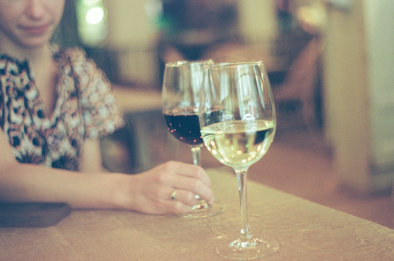 A woman sitting at a table with two glasses of wine